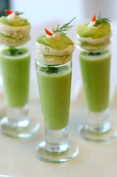 three small cups filled with green liquid and topped with whipped cream