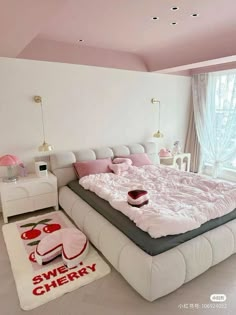 a large white bed sitting in a bedroom next to a window with pink curtains and pillows