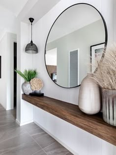 a mirror and vases on a shelf in front of a white wall with text overlay