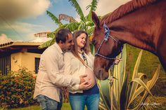 a man and woman standing next to a brown horse in front of a palm tree