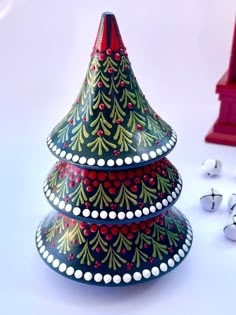 a small christmas tree made out of ceramics on a white surface with earbuds