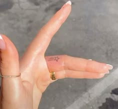 a person's hand with a tiny star tattoo on it, and the fingers are pointed upward