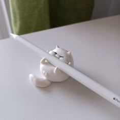 a white pencil with a cat figurine sticking out of it's end