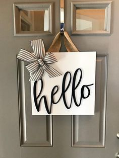 a door hanger with the word hello hanging from it's side and a bow on top