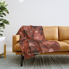 a couch with a blanket on it next to a potted plant