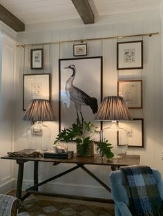 a living room with two lamps and pictures on the wall next to a table filled with plants