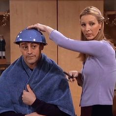 a man getting his hair cut by a woman in a purple shirt and black pants