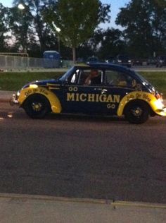 a yellow and blue car with michigan written on it's side driving down the street