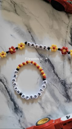 a beaded name bracelet with flowers and beads on top of a marble countertop