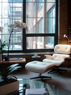 a living room filled with furniture next to a large window covered in lots of windows