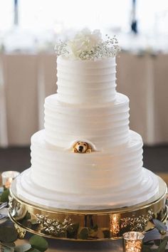 a three tiered white wedding cake on top of a gold platter with flowers