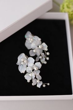 a pair of white flowers with pearls on them in a black and white gift box