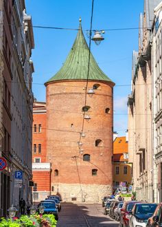 an old brick building with a green roof in the middle of a narrow city street