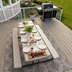 an outdoor dining table with plates and utensils laid out on the outside deck