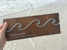 a person holding up a wooden sign with the words thaasophile on it