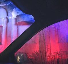 the inside of a car with rain drops on it and colorful lights in the background