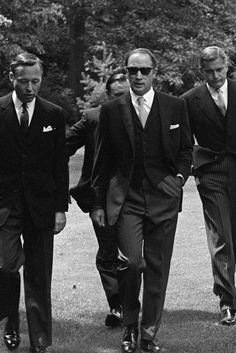 black and white photograph of three men in suits walking down the street with their arms around each other