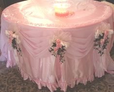 a pink table cloth with flowers and candles on it is set up for a wedding reception