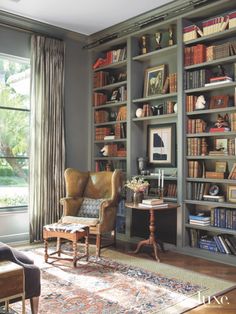 a living room filled with lots of bookshelves next to a chair and table