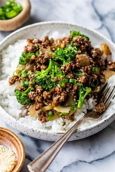 a white bowl filled with rice and broccoli on top of a marble counter