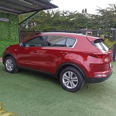 the rear end of a red car parked in front of a fenced off area