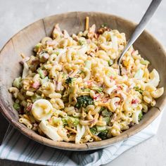 a wooden bowl filled with macaroni salad on top of a blue and white towel