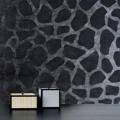 two black and white boxes sitting on top of a table next to a stone wall