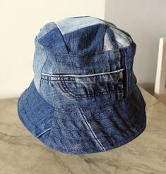 5. Blue jeans bucket hat. For him or her. This hat is made from upcykled blue denim. I sewn it on my lovely vintage sewingmachine. And yes, you can tell this item is handmade and quite unike.  It has a small  zipper pocket and several seams from the fabric, wich use to be trousers. The top of this hat is made from small patches. Inside has a cord in a canal in the lining Inside lining is from light lilac cotton. You can wash in machine, 40 celicius and iron the brim. The brim is sturdy enough to Medium Wash Cotton Bucket Hat With Wide Brim, Medium Wash Denim Bucket Hat For The Beach, Denim Blue Curved Brim Hat For Beach, Medium Wash Cotton Bucket Hat With Short Brim, Cotton Bucket Hat With Short Brim In Medium Wash, Wide Brim Cotton Hat In Medium Wash, Denim Blue Cotton Hat One Size Fits Most, Denim Bucket Hat With Short Brim For Beach, Beach Hat With Curved Brim In Denim Blue