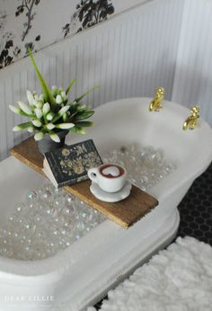 a white bath tub sitting on top of a wooden tray next to a vase filled with flowers