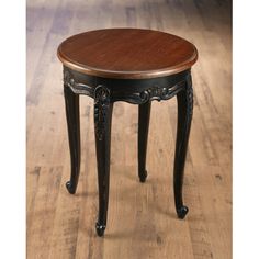 a small wooden table with an ornate design on the top and bottom, sitting on a hard wood floor