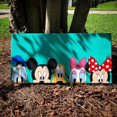 an image of mickey mouse and friends painted on a sign in front of a tree