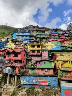 colorful buildings on the side of a hill under a blue sky with clouds in the background