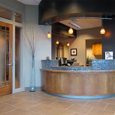 the front desk of an office building with tiled flooring and large circular wooden counter