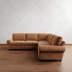 a brown couch sitting on top of a hard wood floor next to a white wall