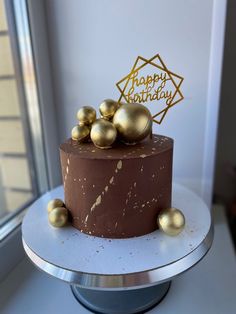 there is a chocolate cake with gold decorations on the top and bottom, sitting in front of a window