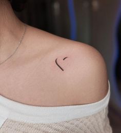 a woman's shoulder with a small heart tattoo on the left side of her neck