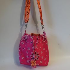 a pink purse with an orange strap hanging from it's side on a white wall