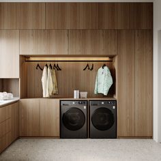 a washer and dryer in a room with wooden cabinets on either side of it