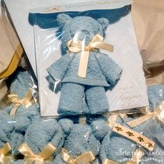 a blue teddy bear with gold ribbon around it's neck sitting in a package