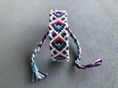 a close up of a beaded bracelet on a gray surface with tassels