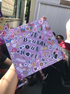 a purple graduation cap that says it's bruad out here with lots of stickers on it