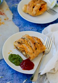 two white plates topped with pastries on top of a blue table covered in food