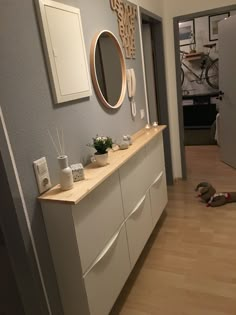 a white dresser sitting next to a mirror on top of a wooden floor in a room