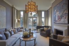 a living room filled with lots of furniture and a chandelier hanging from the ceiling