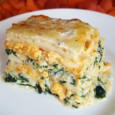 a white plate topped with lasagna covered in cheese and spinach