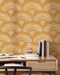 a desk with books on top of it next to a wallpapered background that has an intricate design