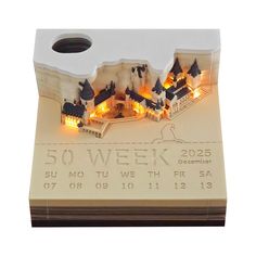 a wooden calendar with buildings and lights on it's sides, in front of a white background