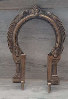 two ornate gold colored metal objects on a marble counter top, one with an open door and the other without it