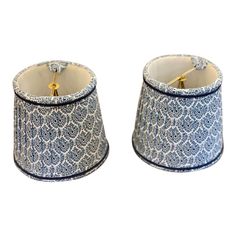 two lampshades with blue and white designs on them, one has a gold handle