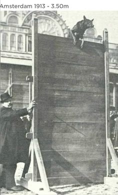 an old black and white photo of men working on a large wooden structure in front of a building